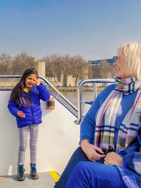Family enjoying a London sightseeing cruise with Tower of London in the background.