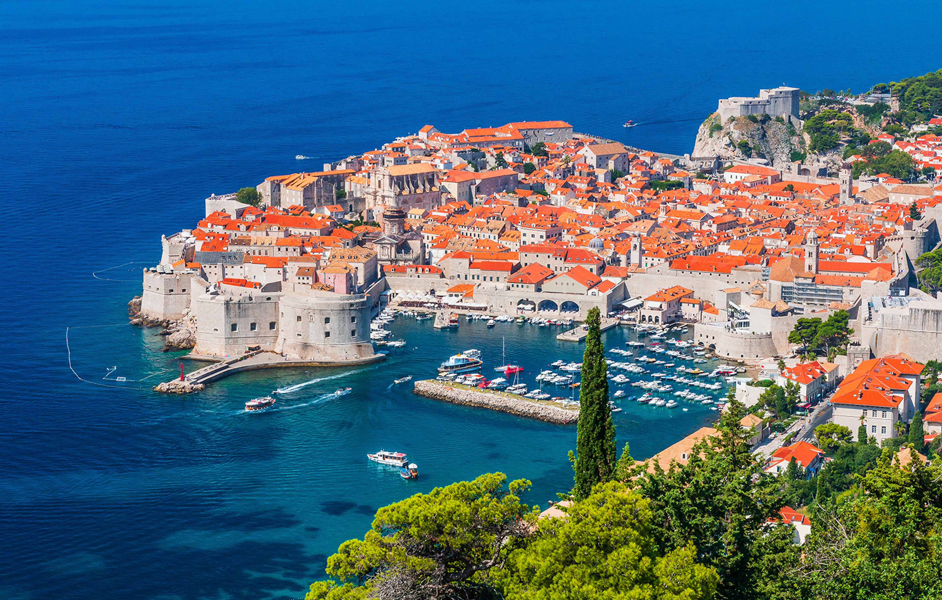 Dubrovnik's Old Town and harbor viewed from above, featuring boats and historic architecture.