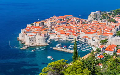 Dubrovnik's Old Town and harbor viewed from above, featuring boats and historic architecture.