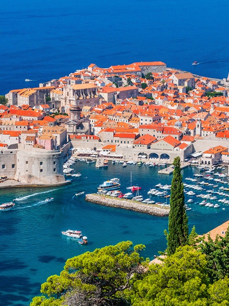 Dubrovnik's Old Town and harbor viewed from above, featuring boats and historic architecture.