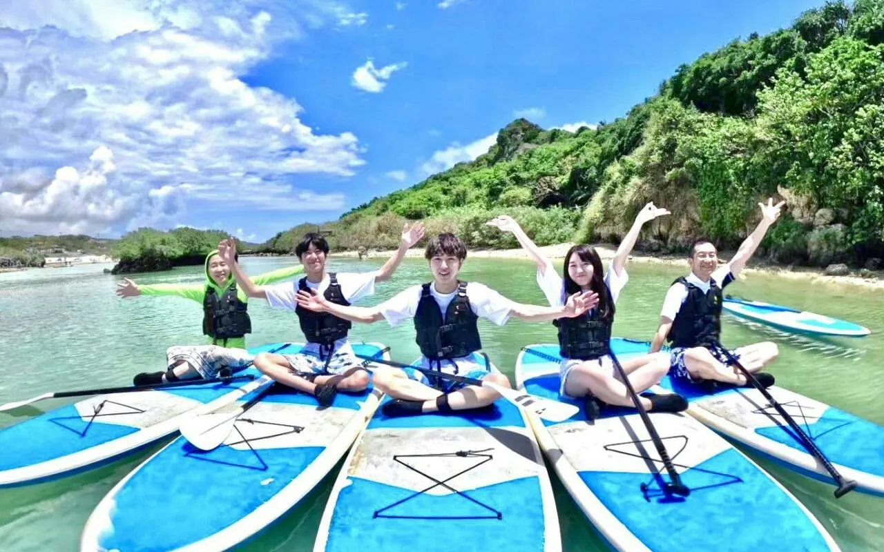 Group enjoying stand-up paddleboarding in clear waters, Miyako Island, Okinawa.