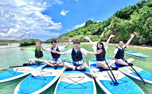 Group enjoying stand-up paddleboarding in clear waters, Miyako Island, Okinawa.