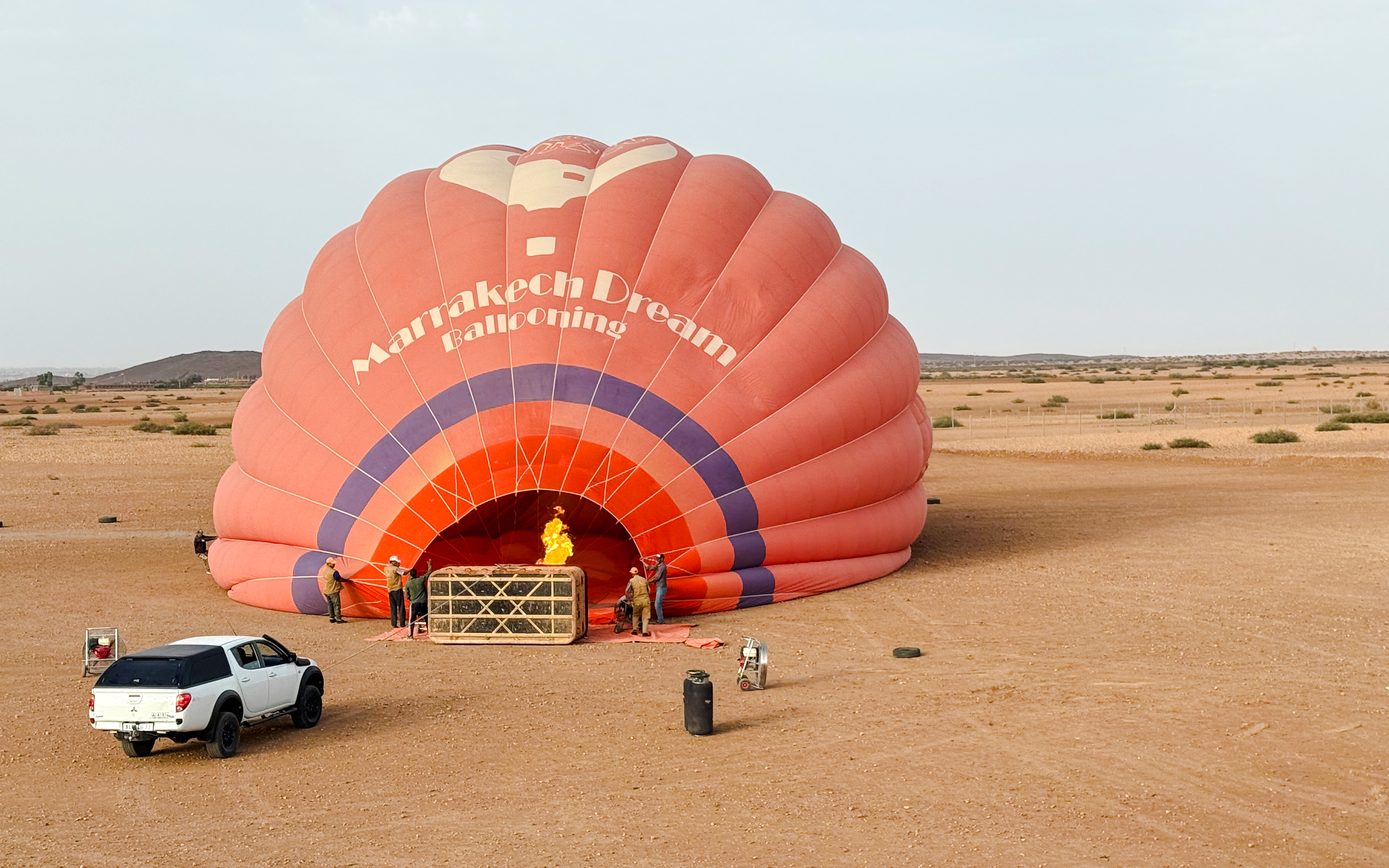 Crew inflating hot air balloon in Marrakech desert.