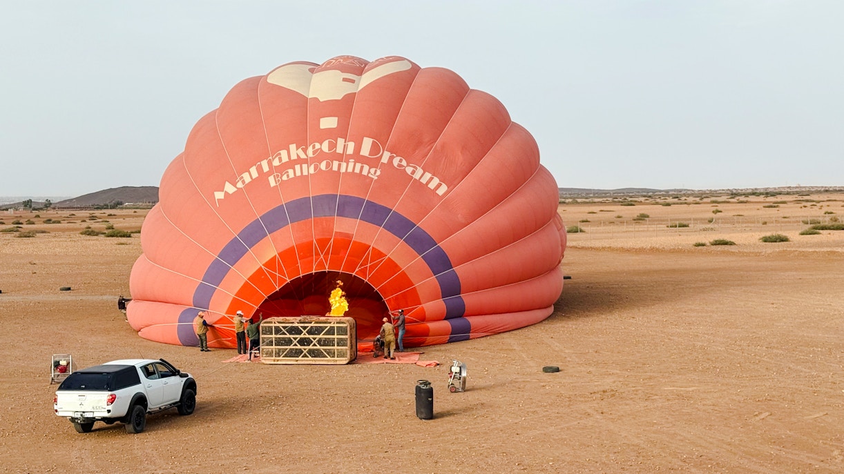 Crew inflating hot air balloon in Marrakech desert.