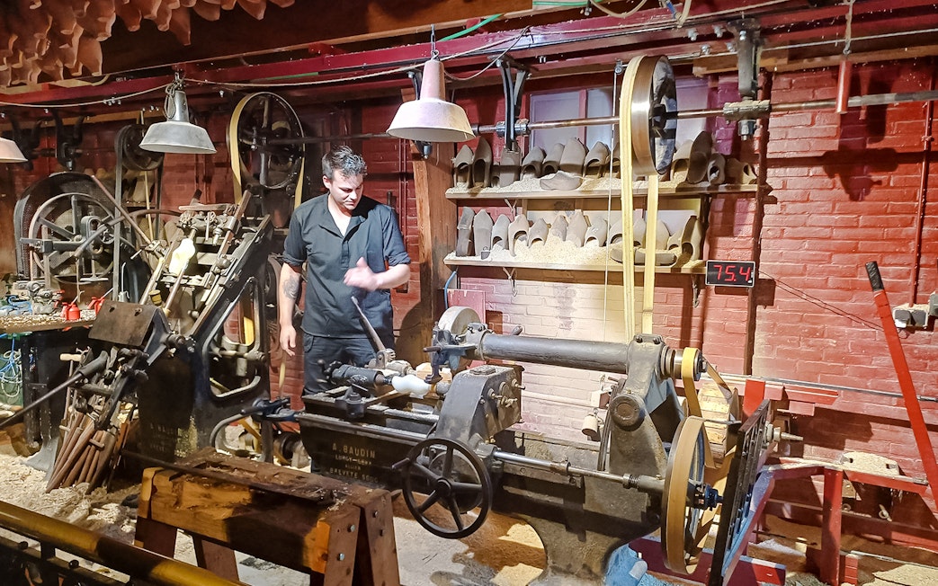 Clog making demonstration with craftsman using machinery in a workshop.