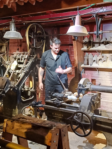 Clog making demonstration with craftsman using machinery in a workshop.