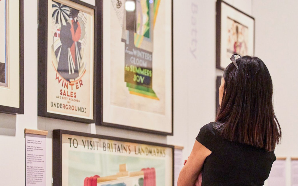 Visitor viewing vintage posters at London Transport Museum.