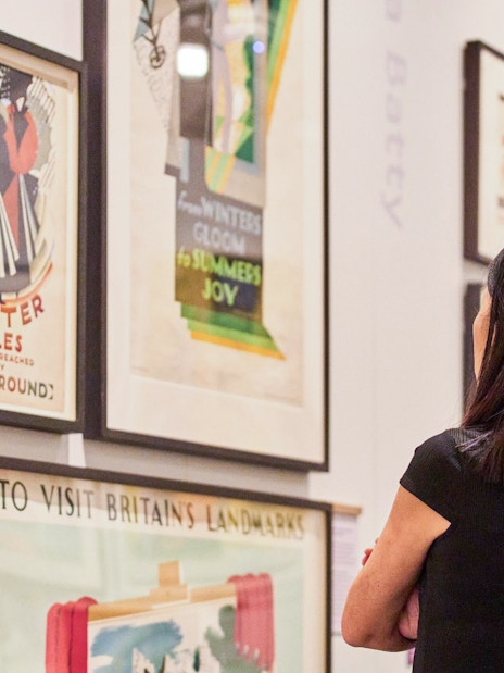 Visitor viewing vintage posters at London Transport Museum.