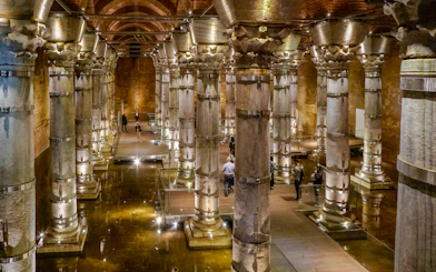 Illuminated columns inside Theodosius Cistern, Istanbul, with visitors exploring.