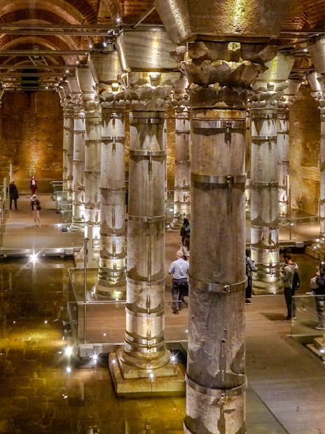 Illuminated columns inside Theodosius Cistern, Istanbul, with visitors exploring.