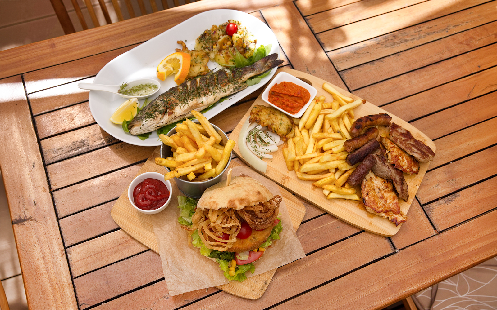 Grilled fish and mixed platter with fries on a wooden table, Lopud Island lunch, Dubrovnik.