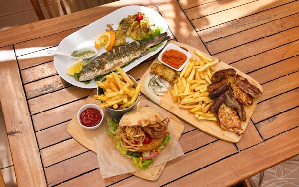 Grilled fish and mixed platter with fries on a wooden table, Lopud Island lunch, Dubrovnik.