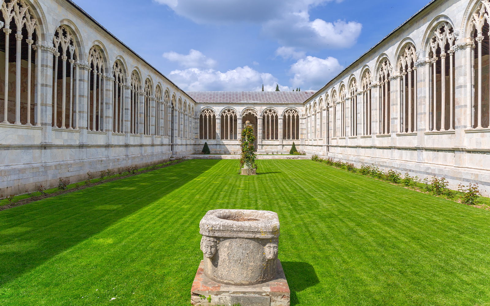 Pisa Camposanto courtyard with Gothic arches and green lawn in Pisa Cathedral Square.