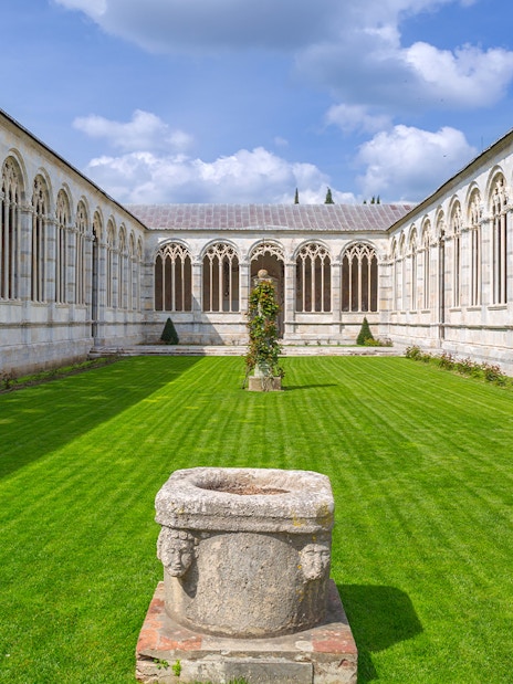 Pisa Camposanto courtyard with Gothic arches and green lawn in Pisa Cathedral Square.