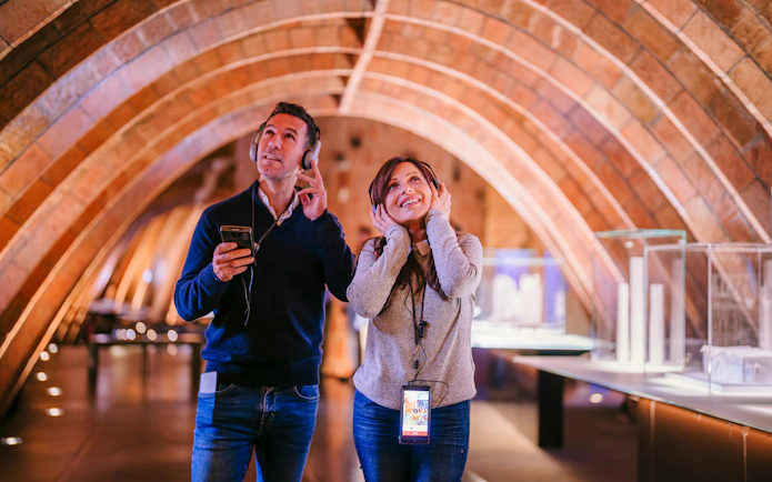 Visitors enjoying an audio tour at La Pedrera - Casa Milà during sunset.