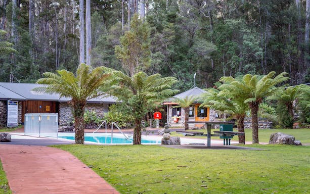 Hastings Caves visitor center with pool and surrounding forest, part of the full-day tour in Huon Valley, Tasmania.