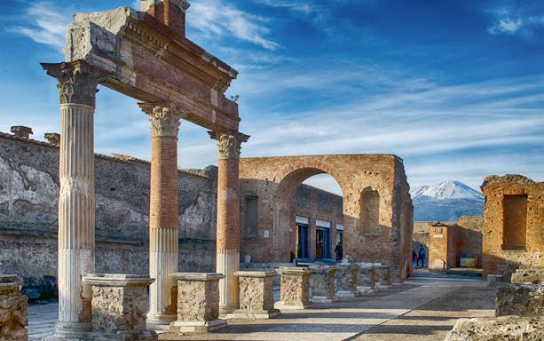 Ancient ruins of Pompeii with Mount Vesuvius in the background.