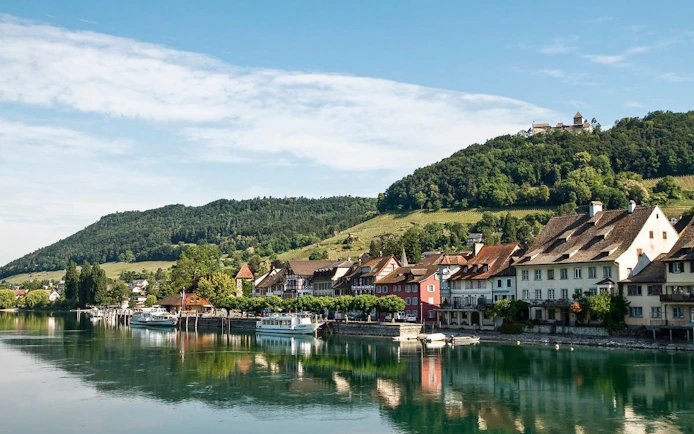 Stein am Rhein village along the Rhine River with medieval buildings and hillside view.