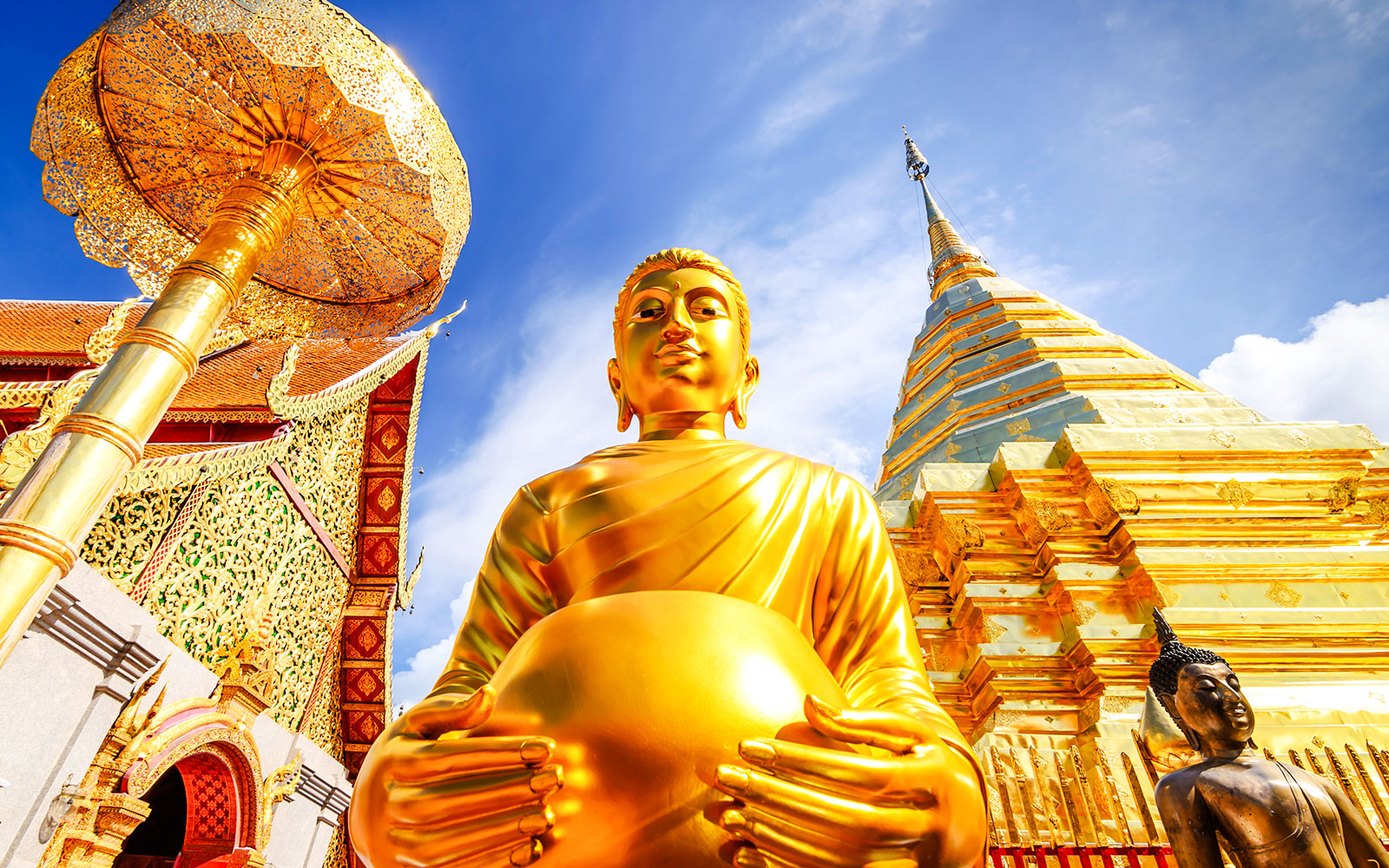 Golden Buddha statue and gleaming chedi at Wat Phra That Doi Suthep, Chiang Mai.