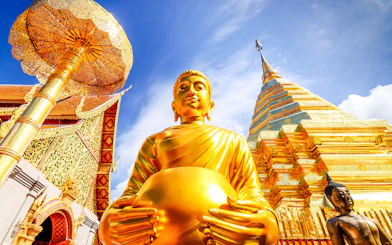 Golden Buddha statue and gleaming chedi at Wat Phra That Doi Suthep, Chiang Mai.