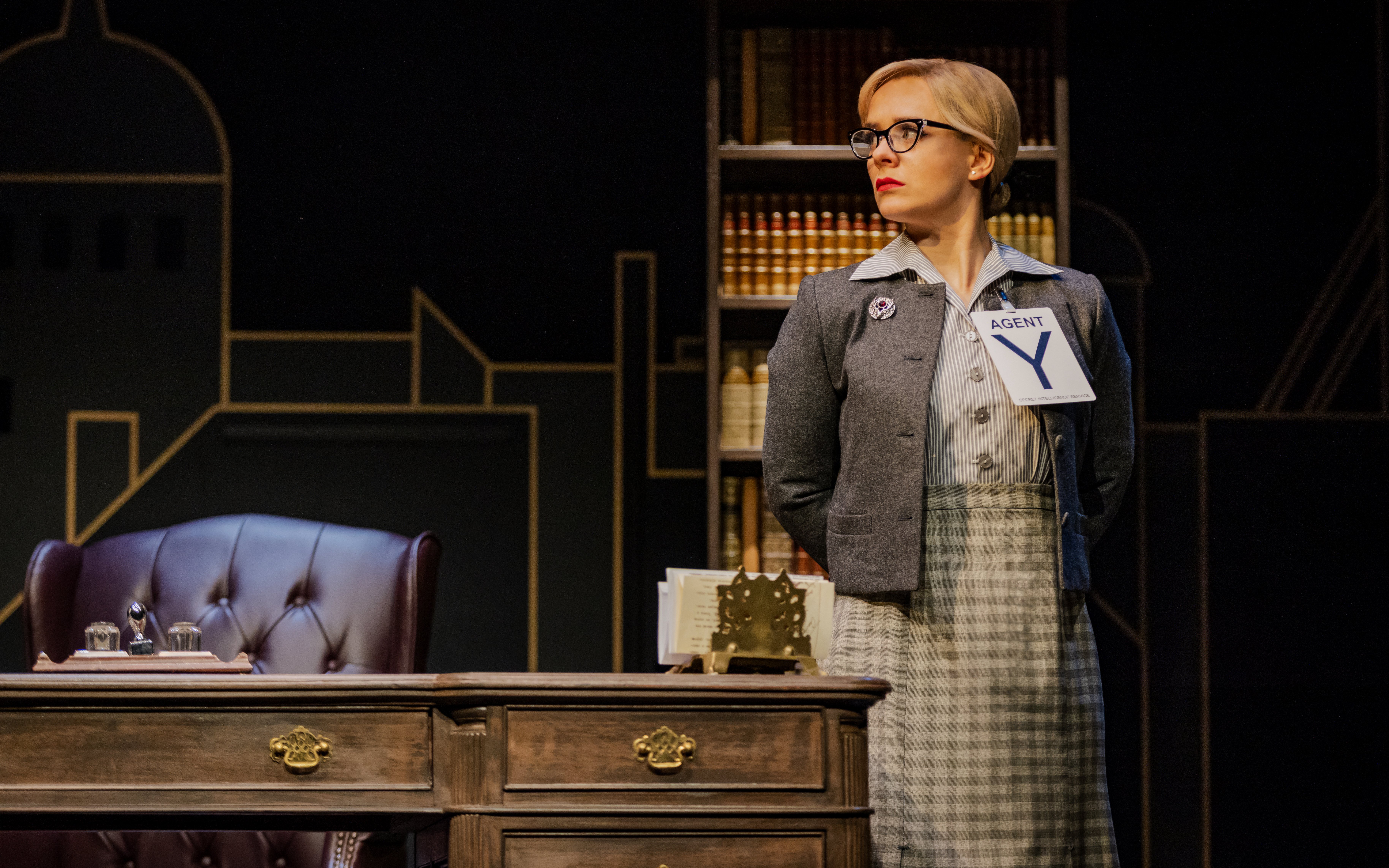 Agent Y standing in an office setting during The Comedy About Spies production.