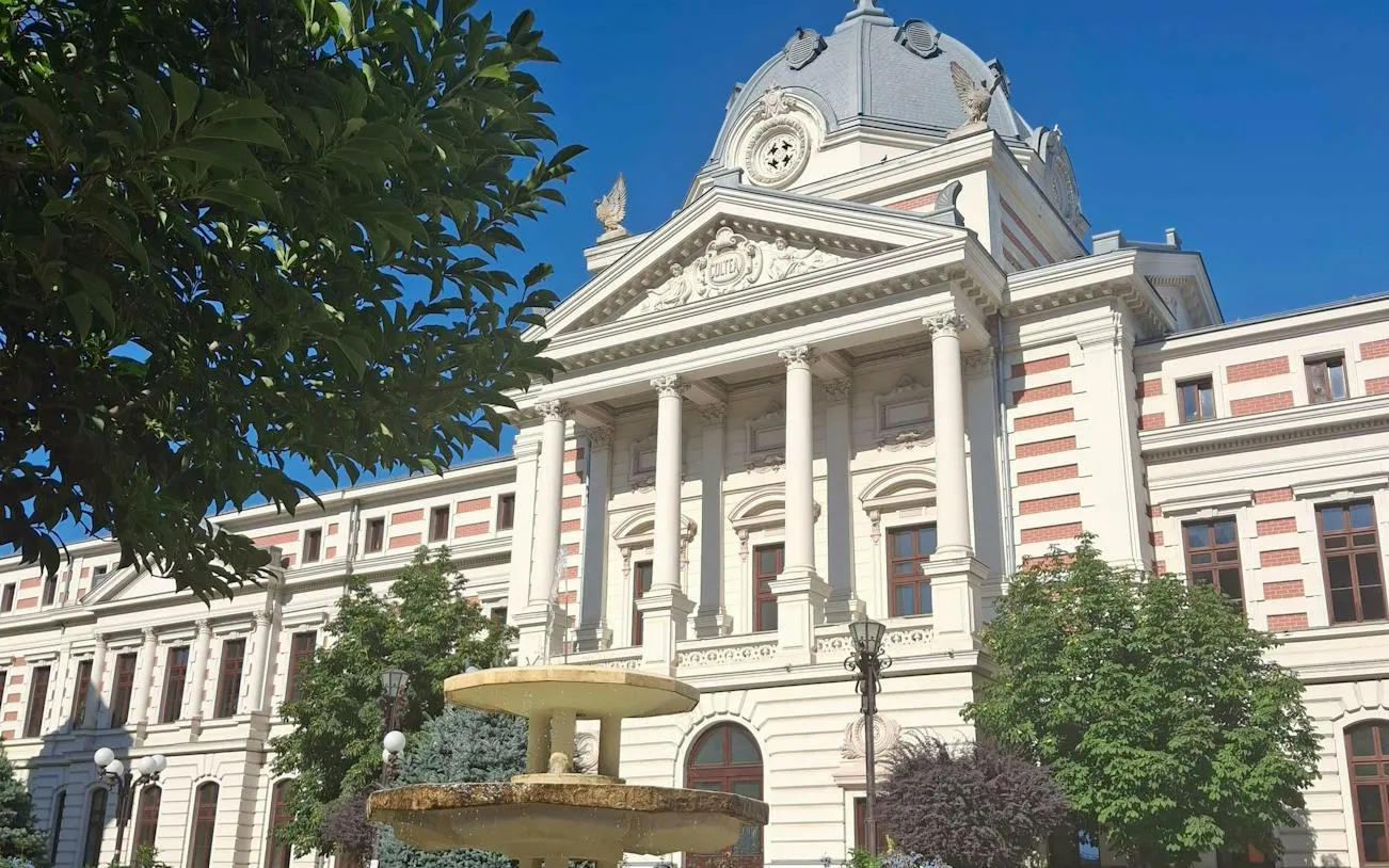 Historic building with columns and fountain, part of The Vanishing Pharmacist game, Bucharest.