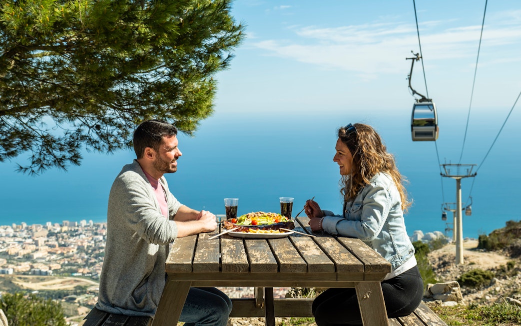 Tourists enjoying lunch with a view of Benalmadena cable car, Malaga, Spain.