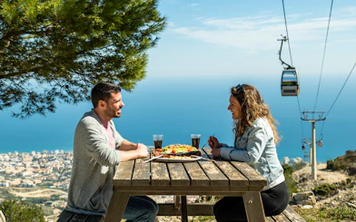 Tourists enjoying lunch with a view of Benalmadena cable car, Malaga, Spain.