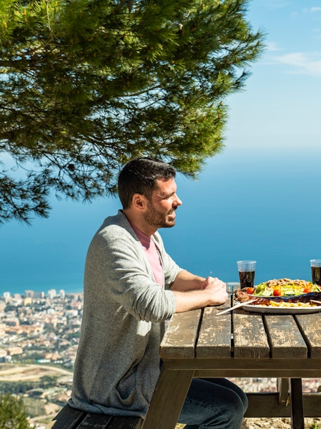 Tourists enjoying lunch with a view of Benalmadena cable car, Malaga, Spain.