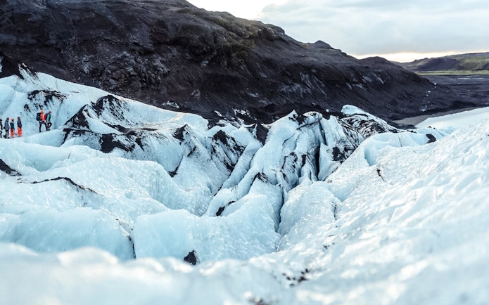 Hikers exploring the icy terrain of Sólheimajökull glacier in Iceland.