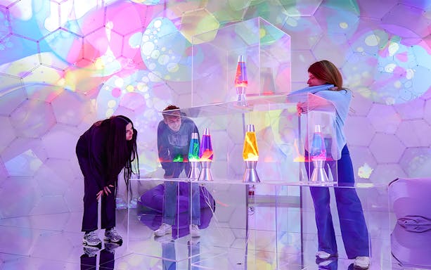 Visitors exploring colorful lava lamps at Bubble Planet immersive experience.