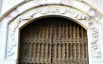 Ornate wooden door with Latin inscription in Naples, part of the Hidden History exploration game.