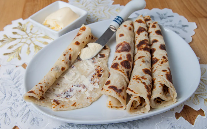 Norwegian lefse with butter on a plate, traditional snack for Aurora borealis tour.