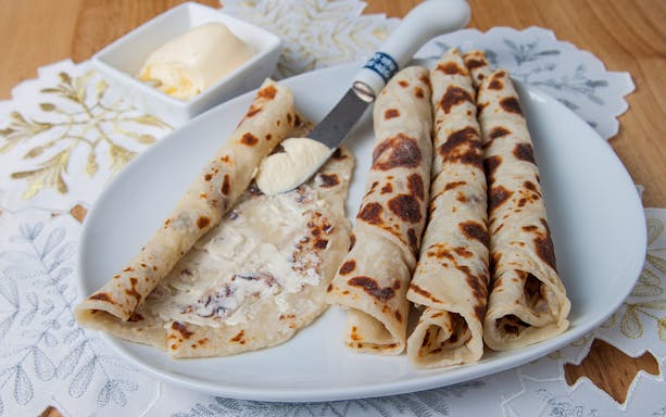 Norwegian lefse with butter on a plate, traditional snack for Aurora borealis tour.