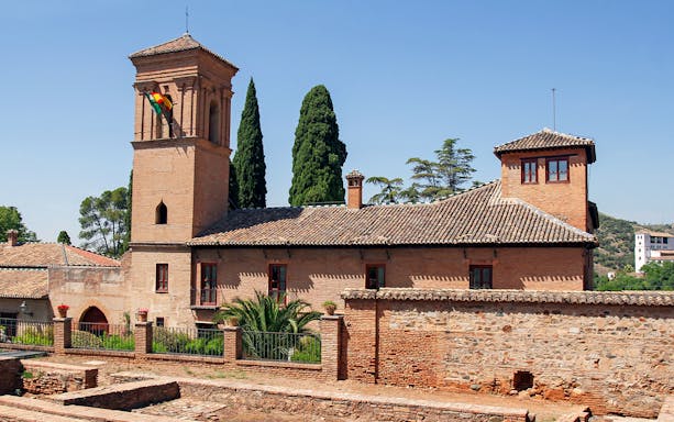 Alhambra Palace exterior with towers and gardens in Granada, Spain.