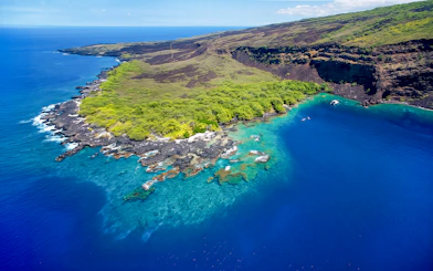 Aerial view of Kealakekua Bay's coastline with lush greenery and clear blue waters, Hawaii.