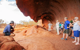 Tour group listening to a guide at Uluru rock formation, Alice Springs.