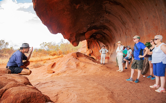 Tour group listening to a guide at Uluru rock formation, Alice Springs.