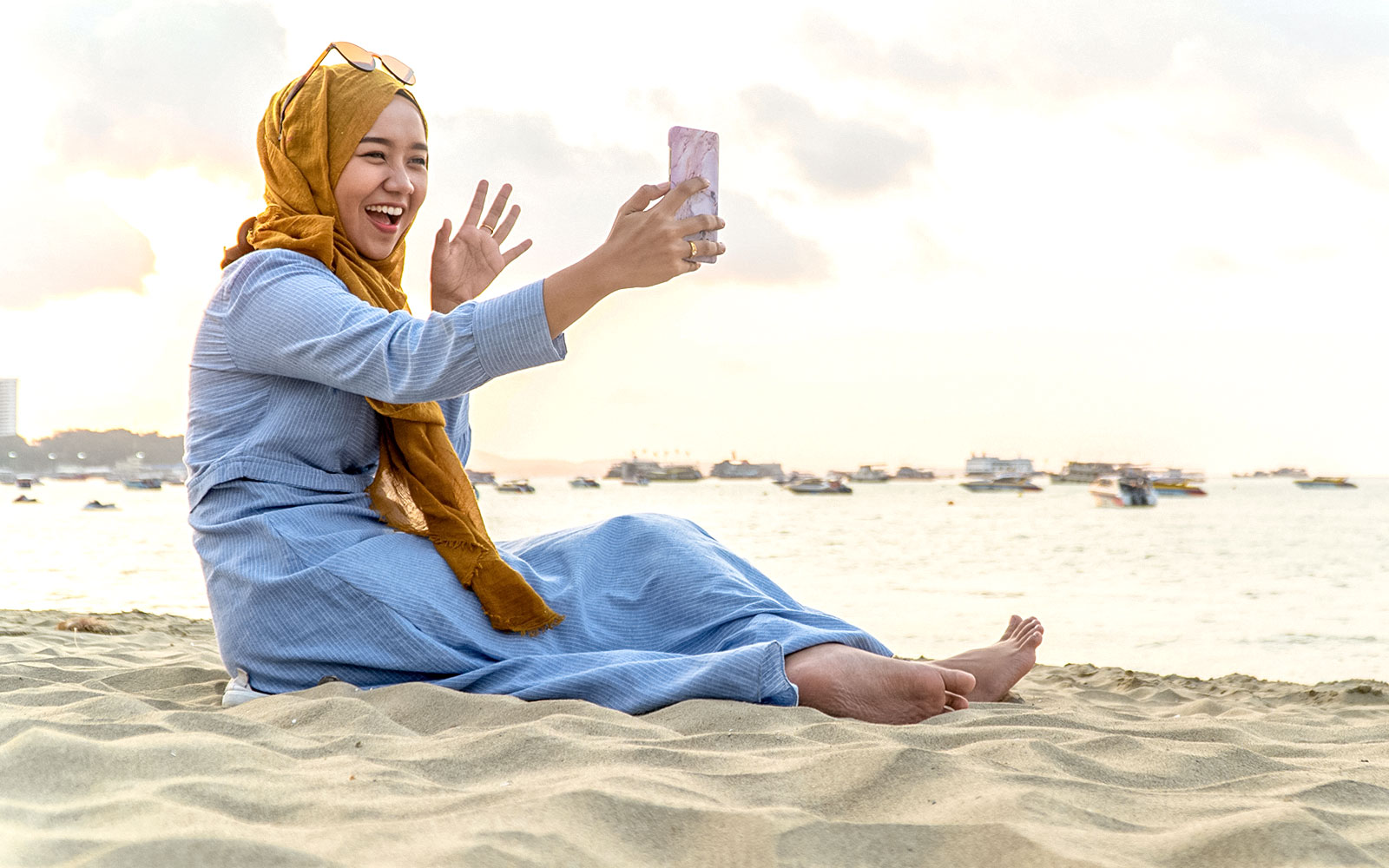 Woman on beach video calling with smartphone, Kuala Lumpur 5G SIM Card.