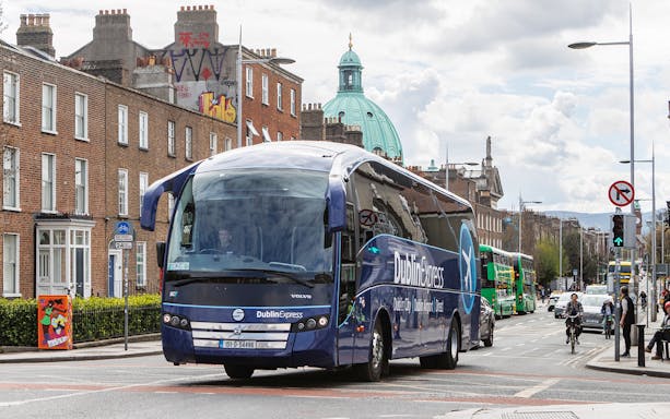 Dublin Express bus on a city street, offering one-way tickets between Belfast and Dublin Airport.