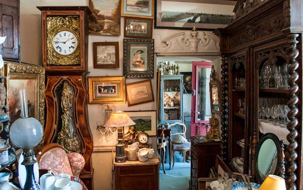 Antique-filled room with ornate clock and paintings inside Hluboká Castle.