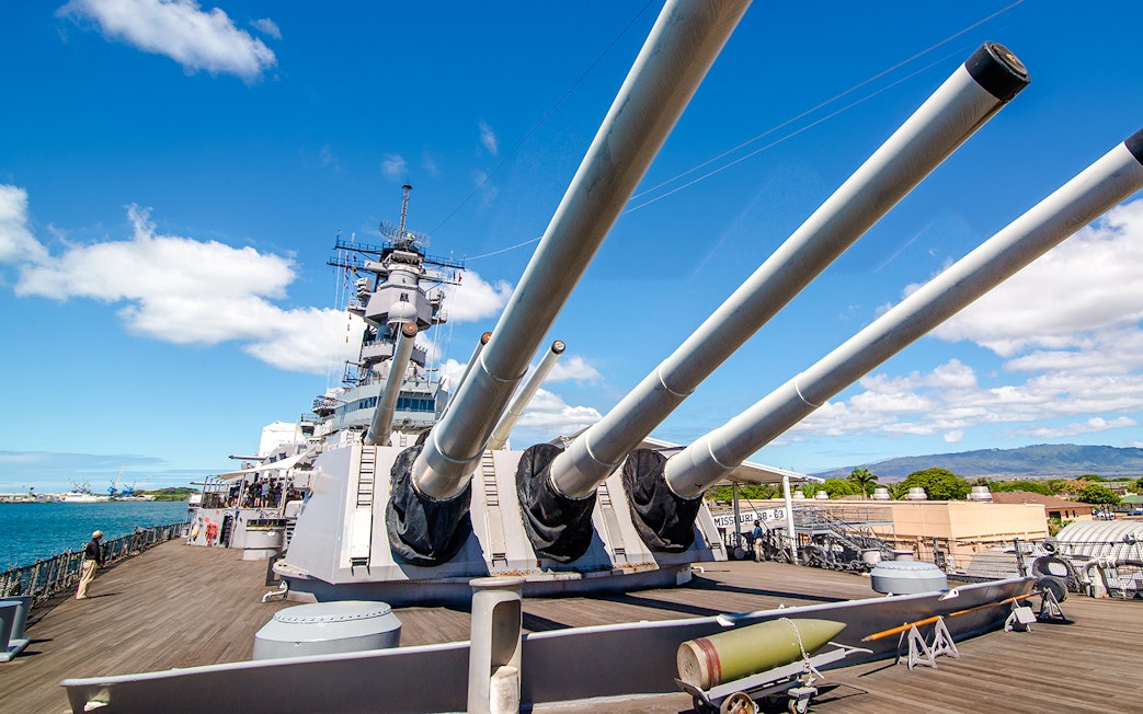 Missouri Battleship Memorial deck with large naval guns under a clear sky.