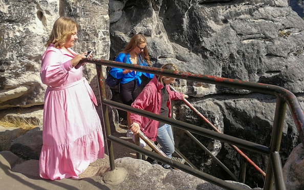 Visitors descending stairs on Bastei Bridge during guided tour in Saxon Switzerland, Germany.