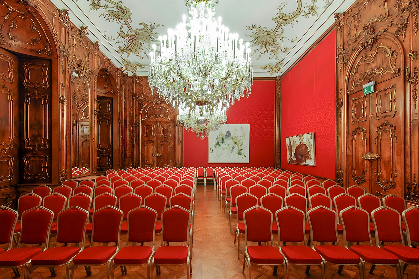 Vienna Baroque concert hall with ornate woodwork and red seating.