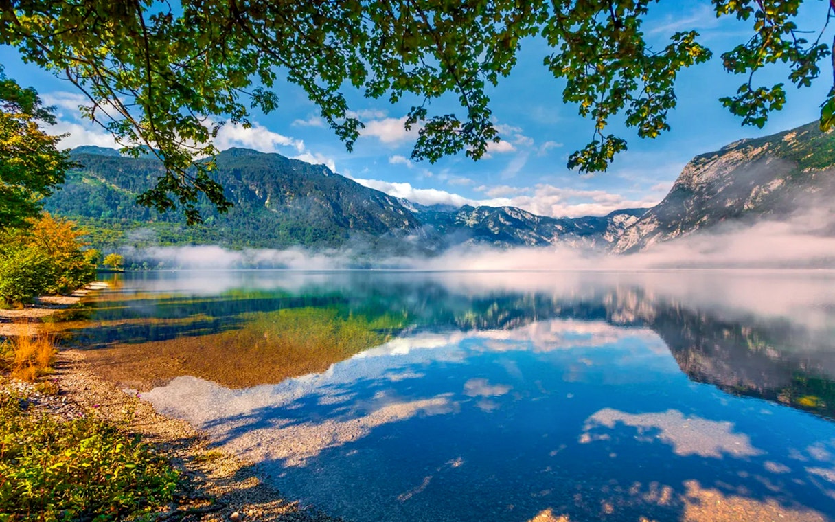 Bohinj Lake with misty mountains and clear reflections in Slovenia.