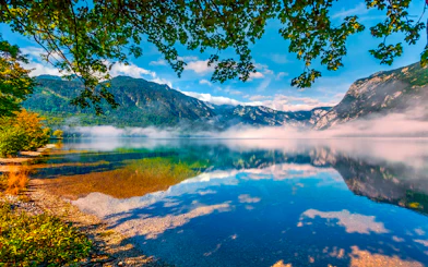 Bohinj Lake with misty mountains and clear reflections in Slovenia.
