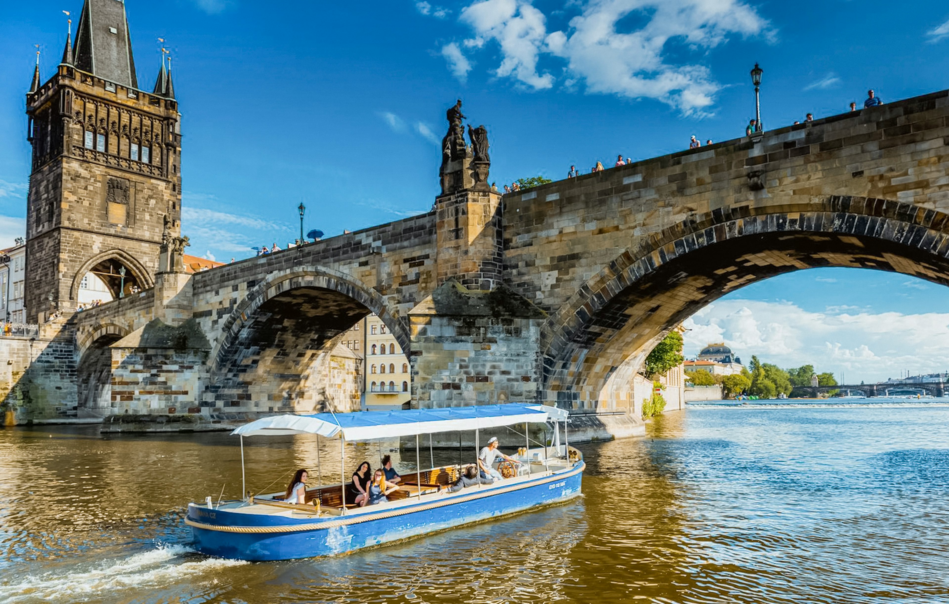 Sightseeing cruise boat passing under Charles Bridge in Prague's Devils Channel.