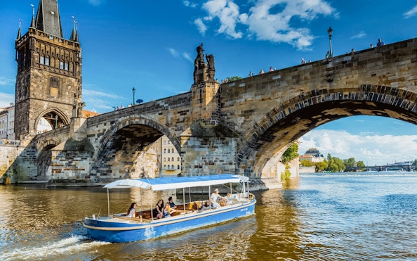 Sightseeing cruise boat passing under Charles Bridge in Prague's Devils Channel.