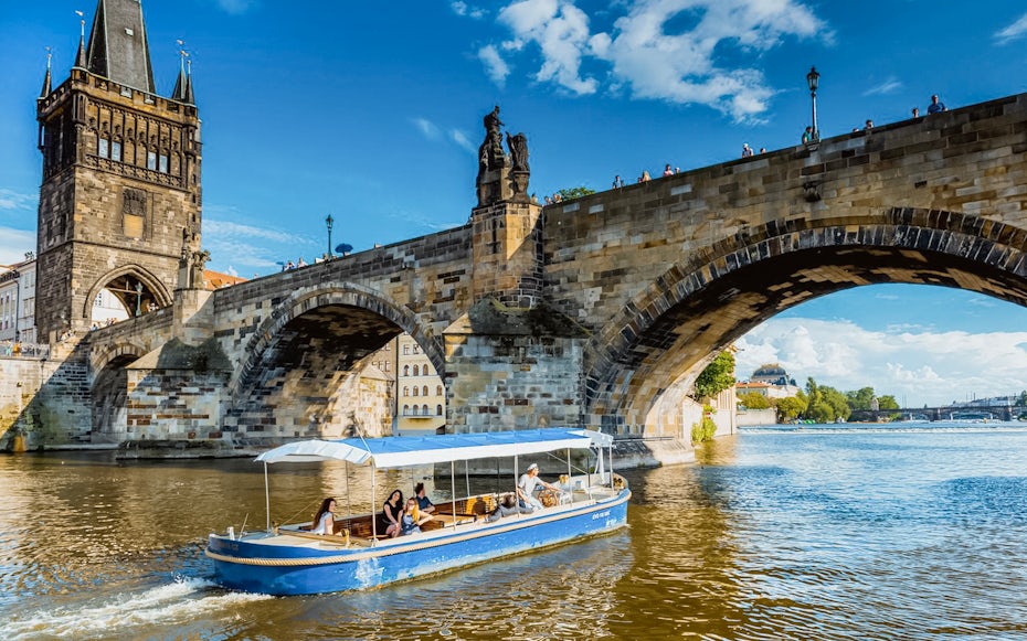 Sightseeing cruise boat passing under Charles Bridge in Prague's Devils Channel.