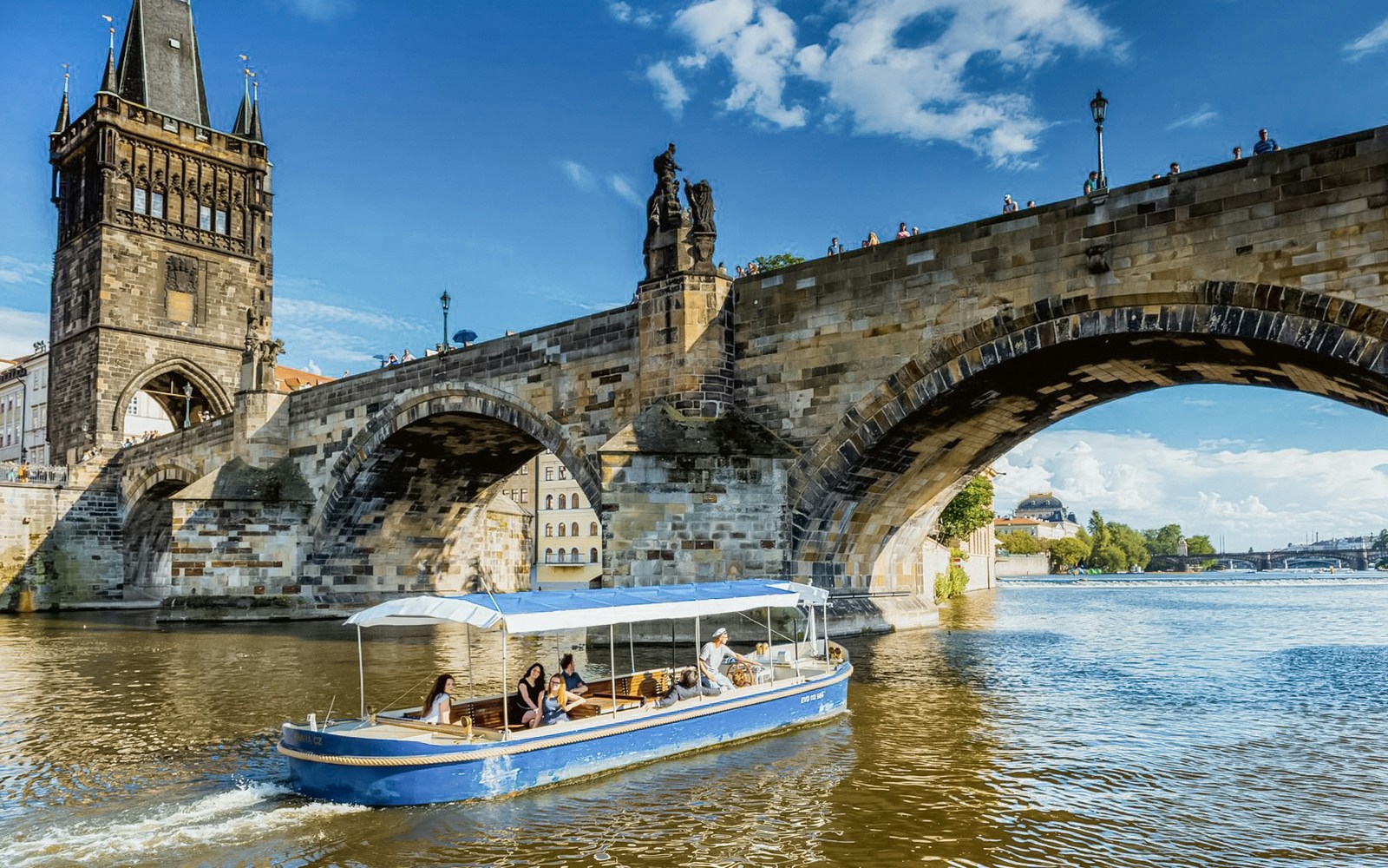 Sightseeing cruise boat navigating Devils Channel in Prague with historic buildings lining the waterway.